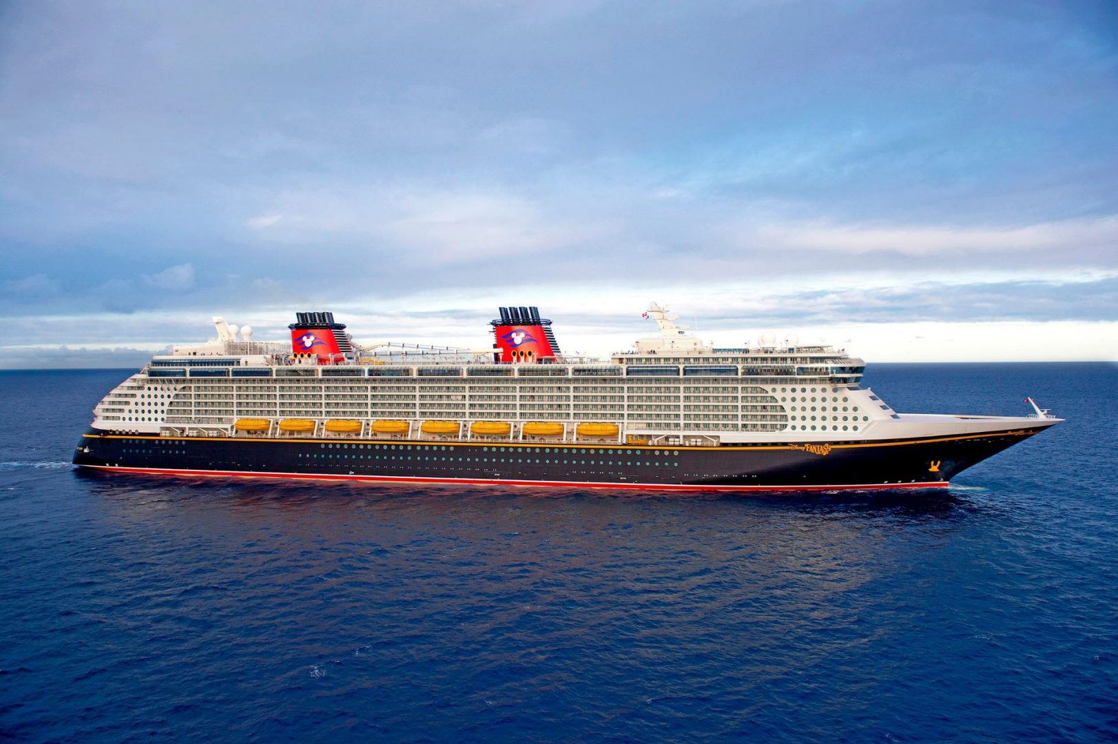 A large Disney cruise ship sailing on open ocean under a blue sky