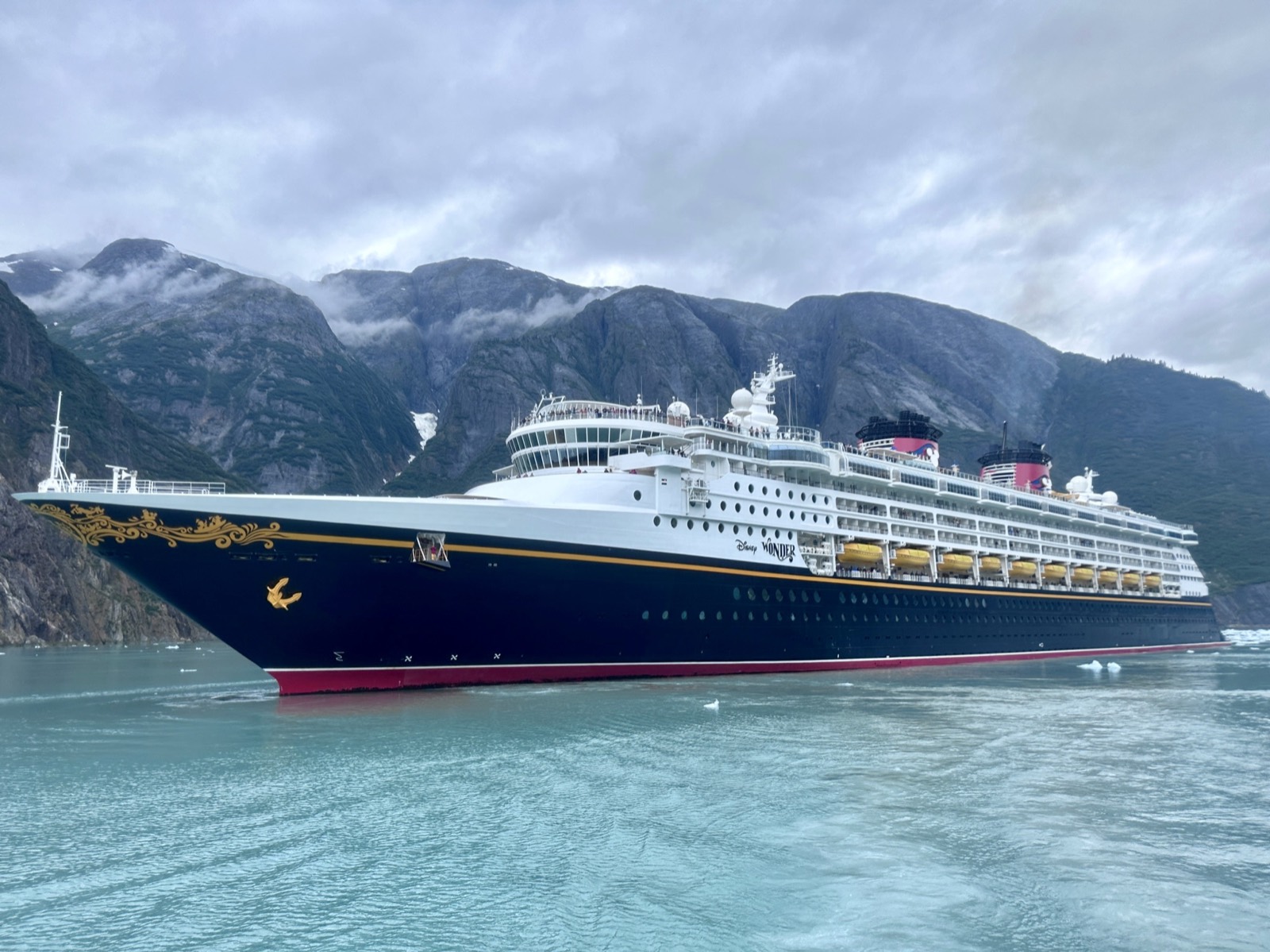 The Disney Wonder cruise ship sailing past glaciers and mountains in Alaska